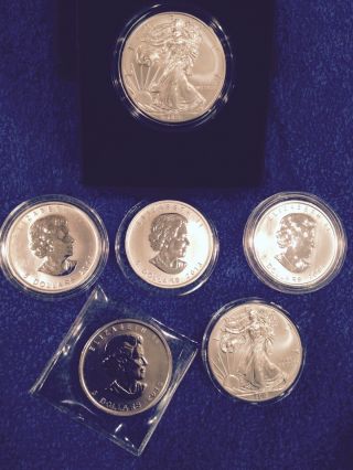Six Silver Dollars: Two American Eagles,  Four Canadian Maple Leafs.  Four Bu photo